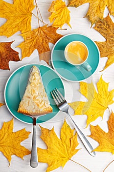 Piece of homemade berry pie decorated with almond petals and cup of coffee espresso on white wooden table