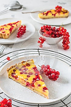 Piece of homemade red currant pie on white background, decorated with fresh red currants