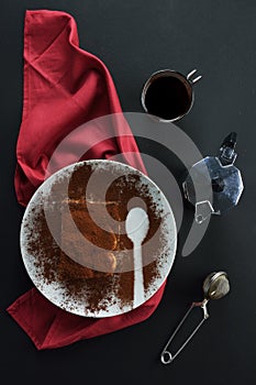Piece of Italian dessert , tiramisu, a red towel,a stainless steel sphere, a espresso coffee maker and cup of espresso coffee