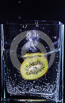 Piece of kiwi in a glass vessel. Black background