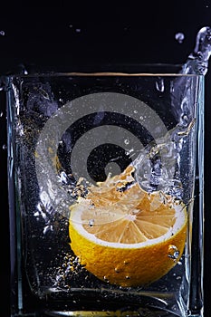 Piece of lemon in a glass vessel. Black background