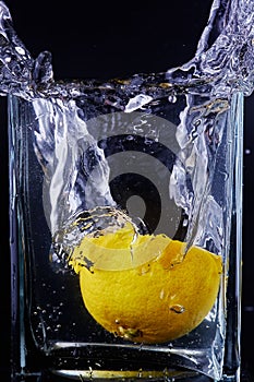 Piece of lemon in a glass vessel. Black background