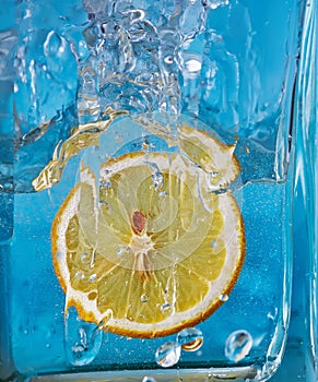 Piece of lemon in a glass vessel. Blue background