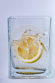 Piece of lemon in a glass vessel. Light background