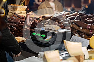 A piece of meat weighed on an electronic scale, traditional festive market stall detail, lots of different types of meat being