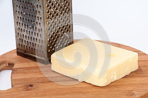 Piece of mozzarella cheese and metal grater on a kitchen wooden