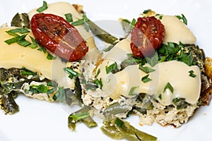 a piece of omelet with herbs and cheese and a sun-dried tomato lying on top