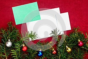 Piece of paper for Christmas wishes on a red background with branches of Christmas tree and Christmas balls