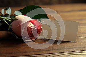 Piece of paper and pink rose on a wooden table, ai generated