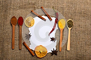 Piece of paper on sackcloth background. Culinary recipe concept. Cinnamon, dried orange and pepper, star anise around