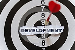 A piece of paper with the text is nailed to the target with a dart - DEVELOPMENT