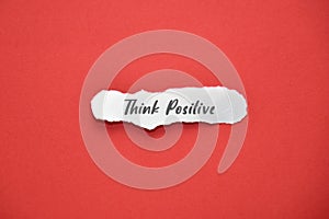 Piece of paper with THINK POSITIVE text on and red background. Lifestyle concept