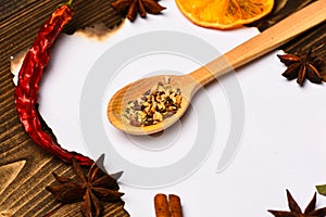 Piece of paper on wooden background. Spices, kitchen herbs lay around white paper. Cinnamon, dried orange and pepper