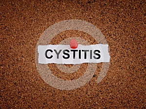 A piece of paper with the word Cystitis on it pinned to a cork board