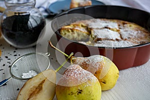 A piece of pear pie for tea on a blue plate on a white table with pears in the foreground