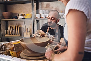 A piece of personality goes into every pot. a young man and woman working with clay in a pottery studio.