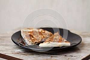 Piece of pizza on black plate