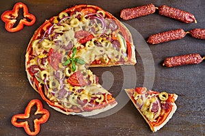 Piece of pizza isolated with salami, tomatoes, bell pepper, onion, green olives, corn, cheese and spices. Sliced pizza