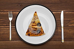 A piece of pizza on white plate with a knife and fork on wooden background. Slice of tasty pizza on the plate. Top view