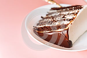Piece of puff chocolate cake on round plate with small fork