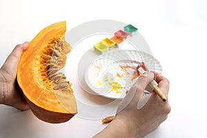 A piece of pumpkin in the hands. A man paints a pumpkin in watercolor. The concept of a good mood. Creative work
