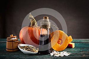 Piece of pumpkin, pumpkin seeds in sackcloth bag and wooden barrel, hemp seed and oil bottle. Close up.