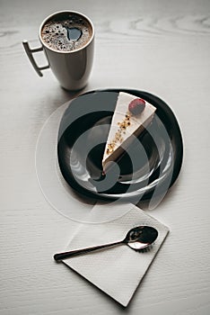 Piece of raspberry cheesecake dessert with coffee in a white cup on  table in a cafe