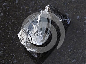 piece of raw Obsidian (volcanic glass) on dark photo