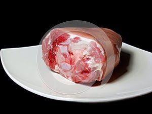 A piece of raw pork knuckle in a pan