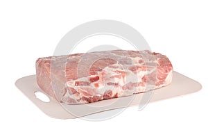 Piece of raw pork meat on a plastic cutting board over a white background.