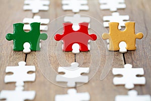 Piece of Red green and gold jigsaw puzzle On the old wood And green background. teamwork concept. symbol of association and