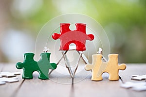 Piece of Red green and gold jigsaw puzzle On the old wood And green background. teamwork concept. symbol of association and