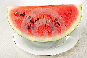 Piece of red watermelon in white plate on wooden table