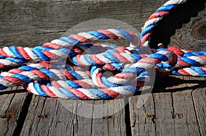 A piece of red, white and blue rope coiled on a dock