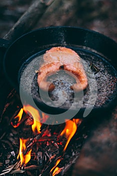 A piece of salmon in a pan over a fire. Cooking in nature. Grilled fish