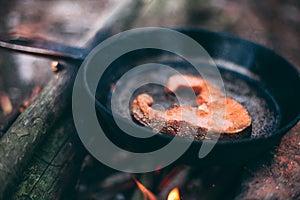 A piece of salmon in a pan over a fire. Cooking in nature. Grilled fish