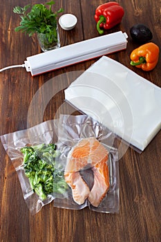 A piece of salmon in a vacuum bag and broccoli next to a pack of vacuum bags