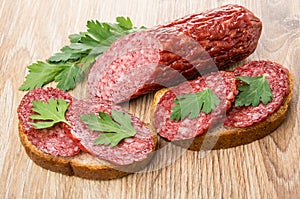 Piece of sausage and sandwiches with smoked sausage and parsley