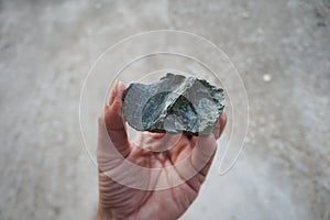 A piece of serpentine rock specimen in a hand. Serpentinite a metamorphosed ultramafic rock.