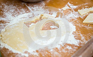 Piece of short pastry on brown wooden table poured with flour wi