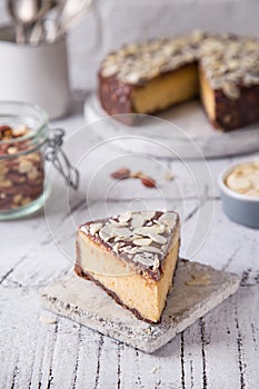 Piece Slice of ÃÂ¡heesecake with Chocolate, Caramel, Peanut Paste, Nougat Layered Cake on white table background