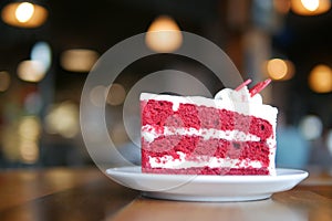 Piece of sliced red velvet cake in ceramic plate on wood table