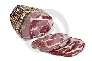 Piece and slices of traditional Croatian dried pork neck, pork collar bacon, on white background