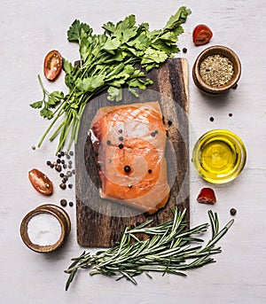 Piece of smoked salmon on a cutting board with herbs and spices wooden rustic background top view