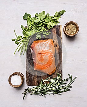 Piece of smoked salmon on a cutting board with herbs spices on wooden rustic background top view