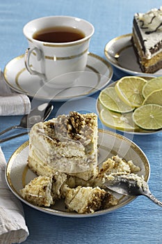A piece of sponge cake on a white plate with a Cup of tea