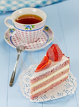 A piece of strawberry cake with a cup of tea