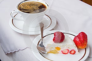 Piece of strawberry dessert on white plate and Cup coffee