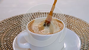 Piece of sugar falls into a cup of espresso coffee