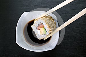 Piece of sushi dipping in soy sauce